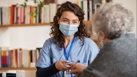 Masked female employee providing home health services