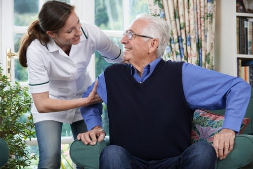 senior care employee assisting a resident from his chair